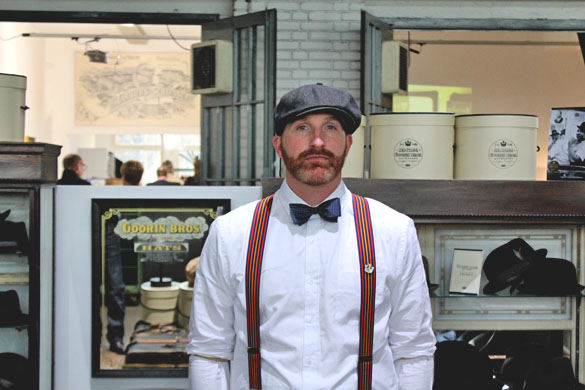 a dapper man wearing goorin bros flatcap, bowtie and suspenders